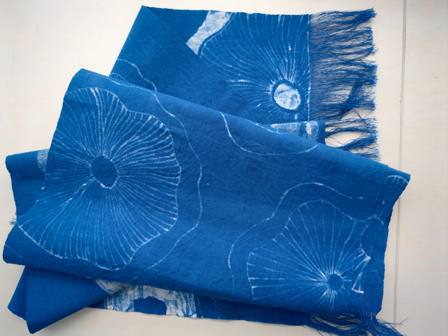 Blue fabric with white floral patterns and fringes on a white background