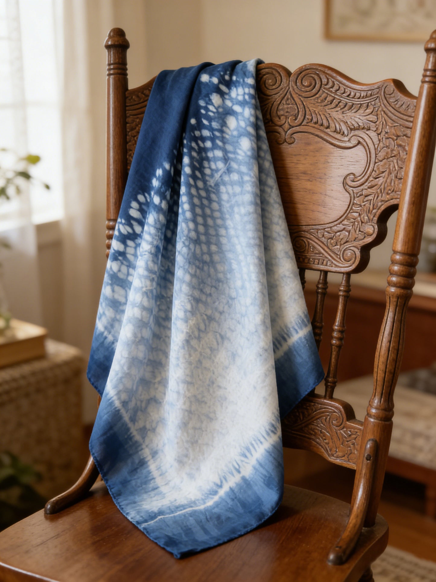 Blue and white tie-dye blanket draped over a wooden chair in a home setting.