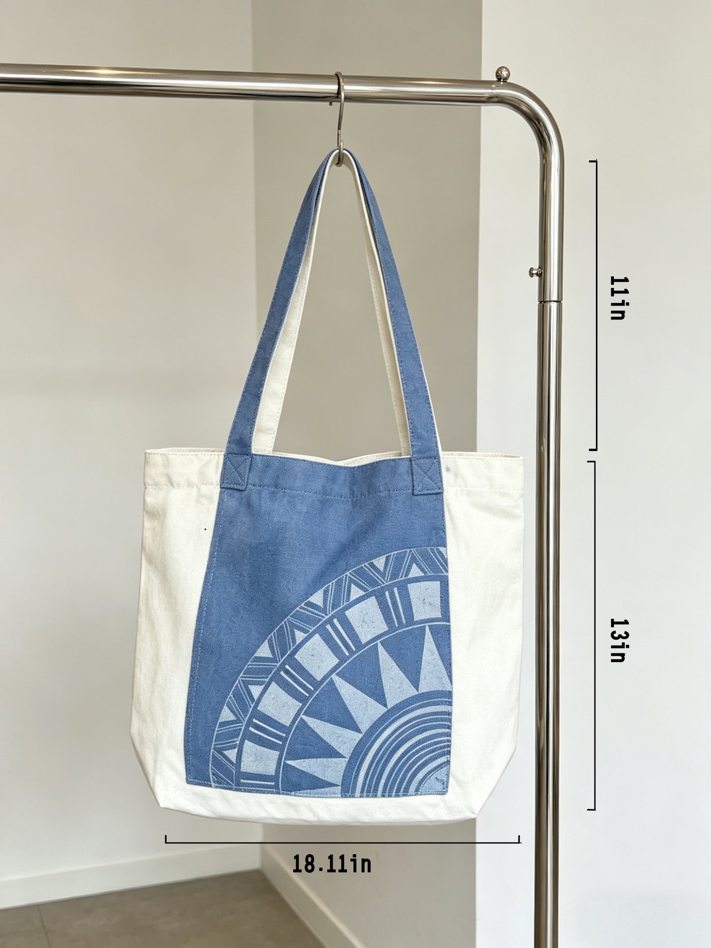 Tote bag with blue geometric pattern hanging on a rack, with dimensions displayed.