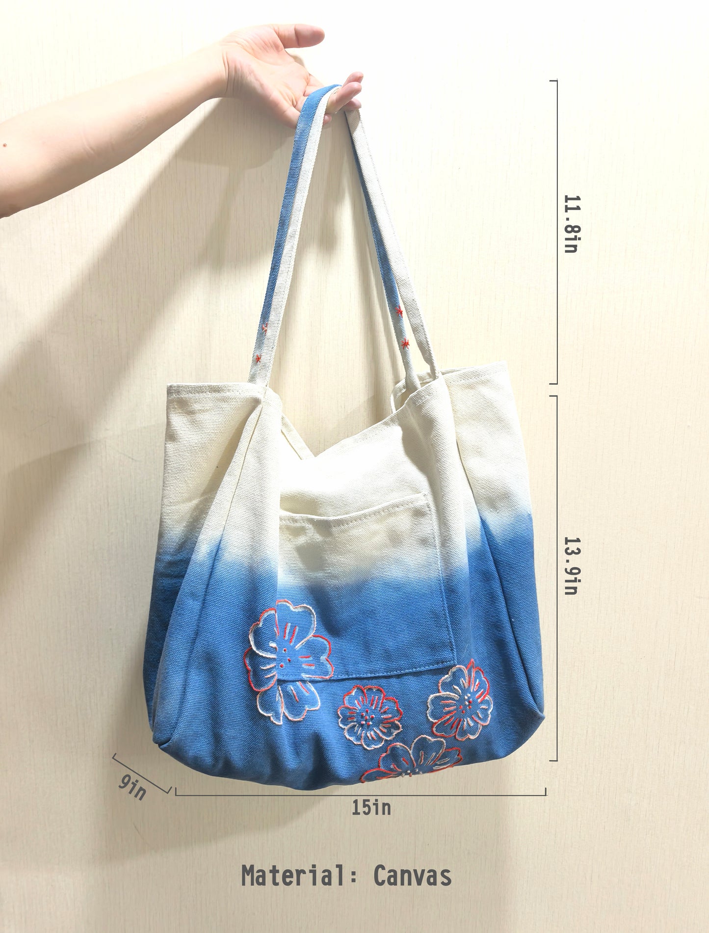 Handbag with blue gradient and floral design, held by a hand, with dimensions and material information.