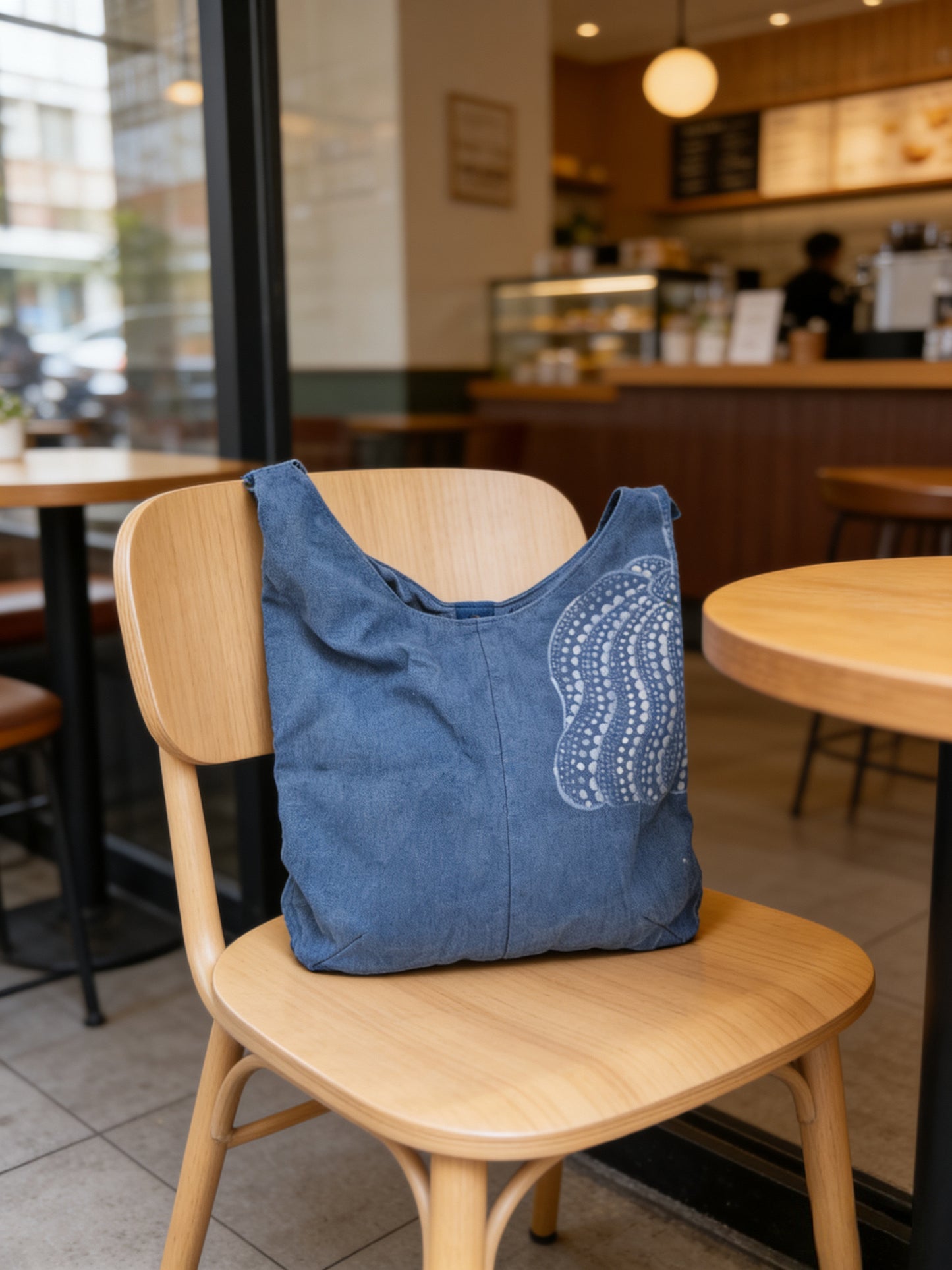 Blue bag with white patterns on a wooden chair in a cafe setting