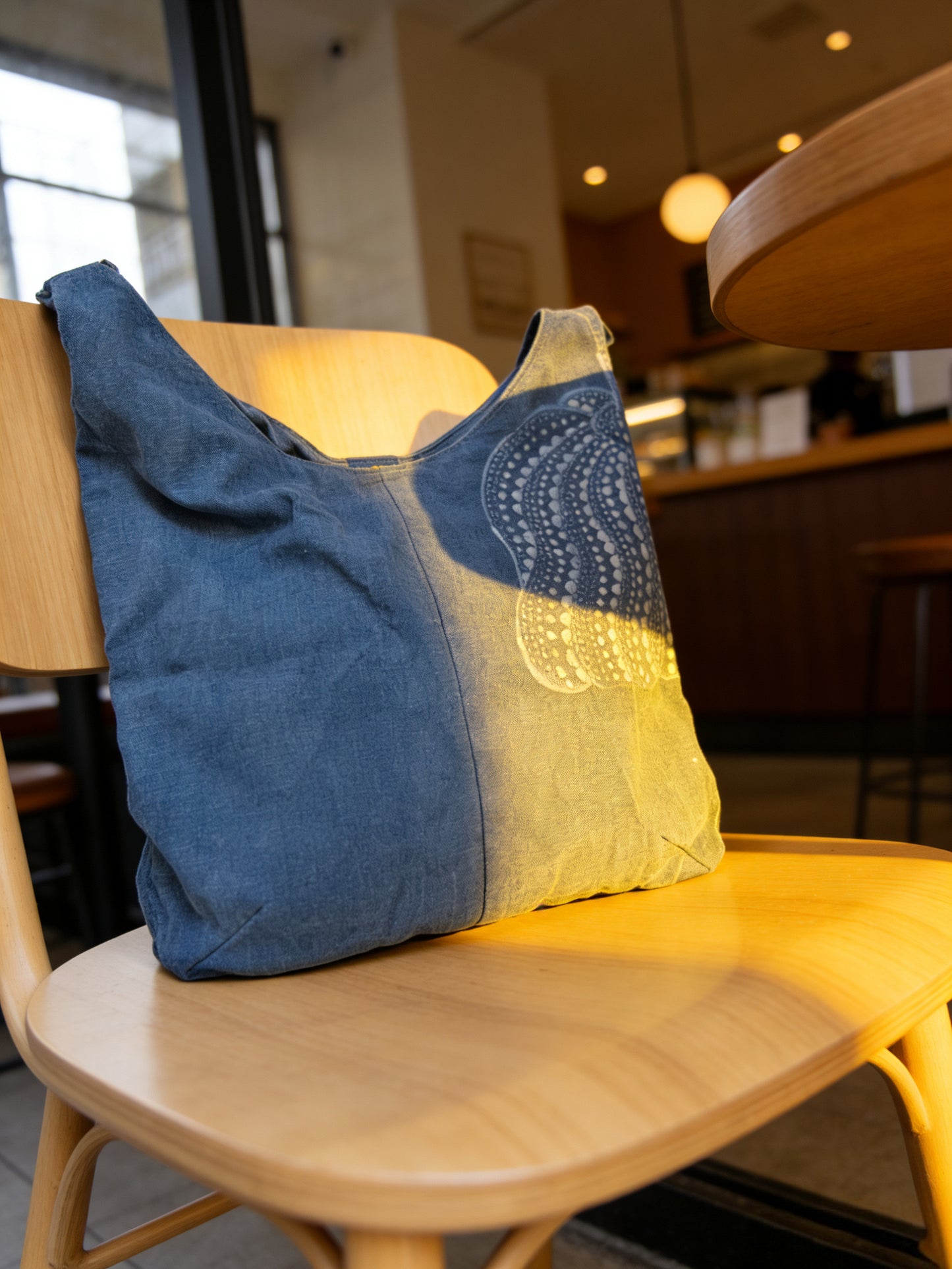Blue and yellow tote bag on a wooden chair in an indoor setting