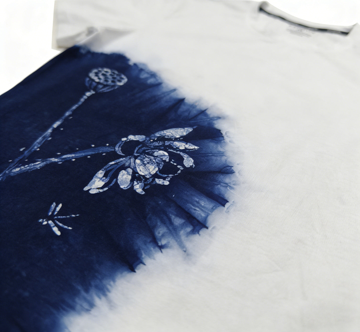 White t-shirt with blue tie-dye design featuring floral patterns on a white background