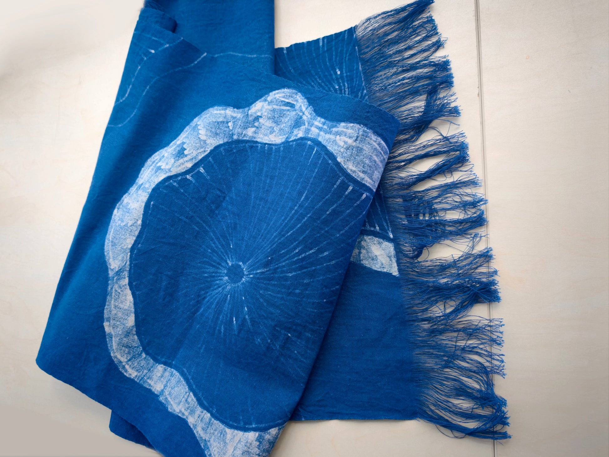 Blue and white patterned fabric with fringe on a light background
