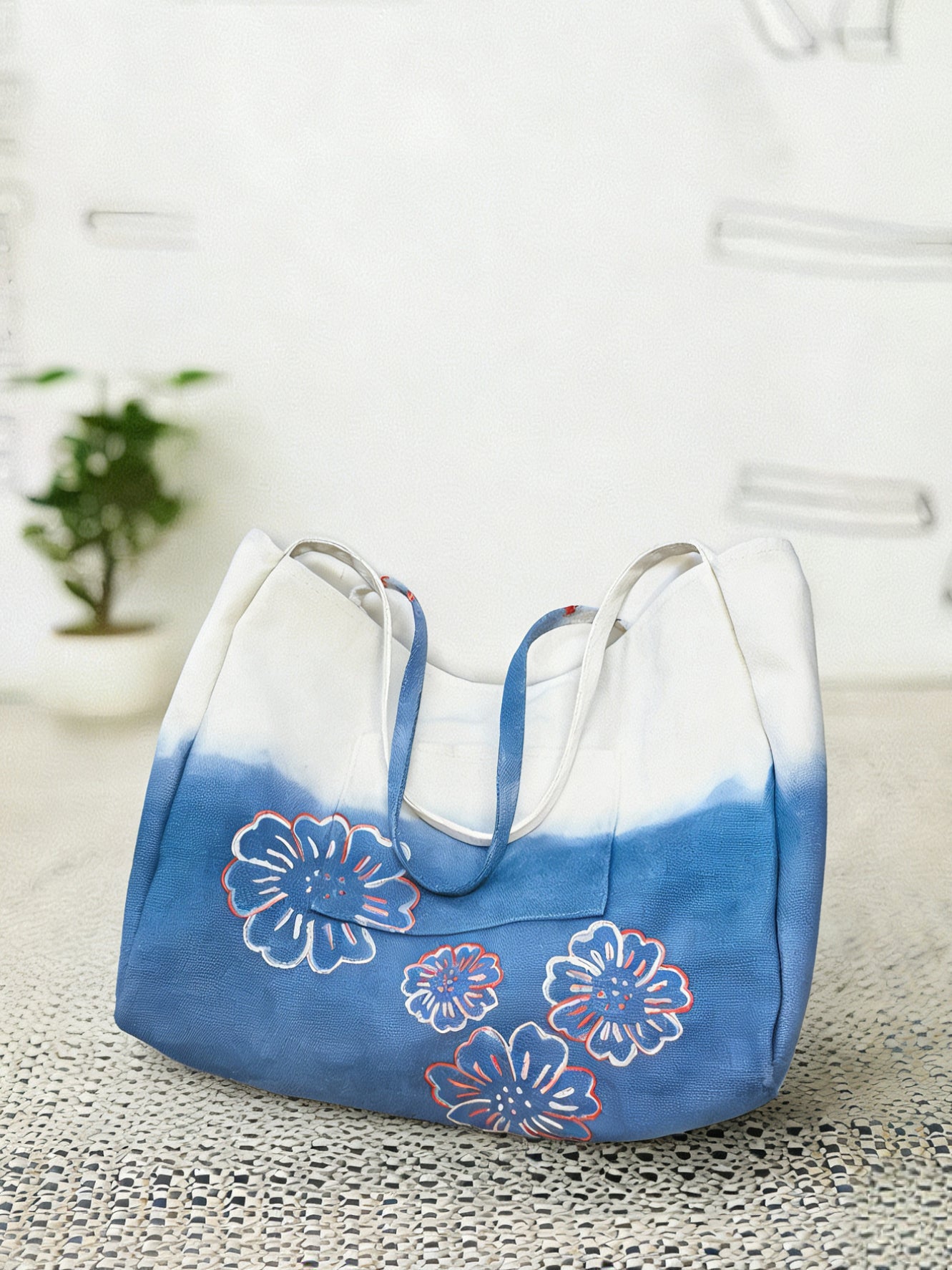 Blue and white tote bag with floral designs on a textured surface.