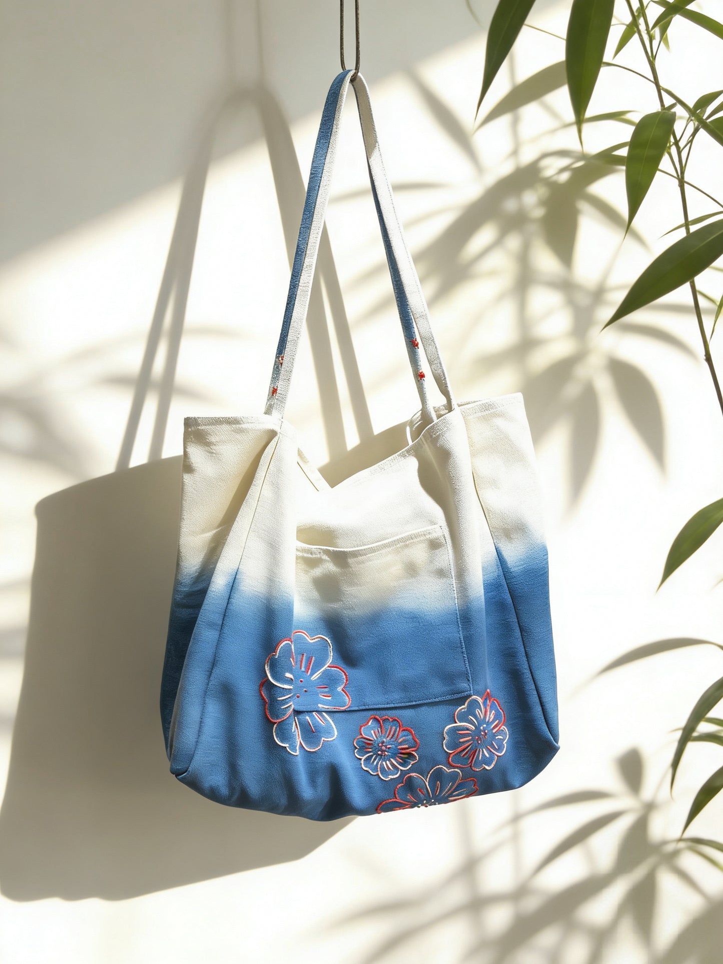 Tote bag with blue and floral design hanging against a light background