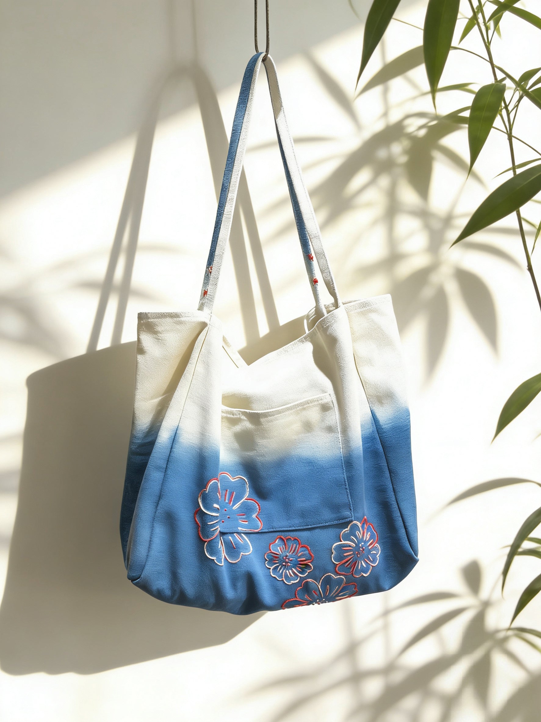 Tote bag with blue and floral design hanging against a light background