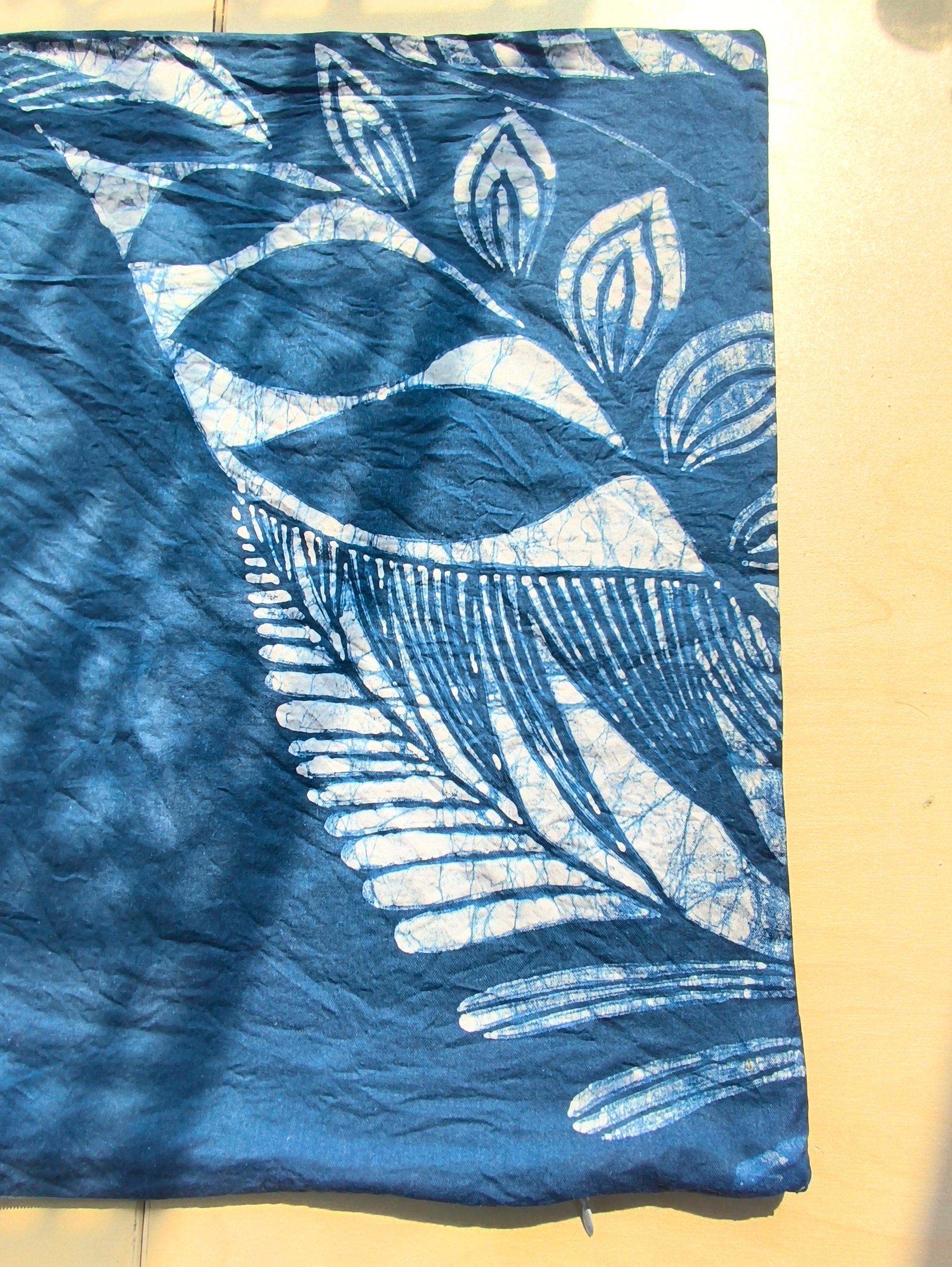 Blue fabric with white leaf pattern on a beige surface