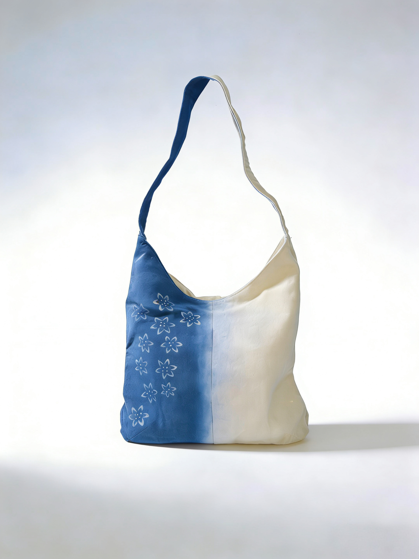 Two-toned blue and white bag with floral patterns on a light gray background