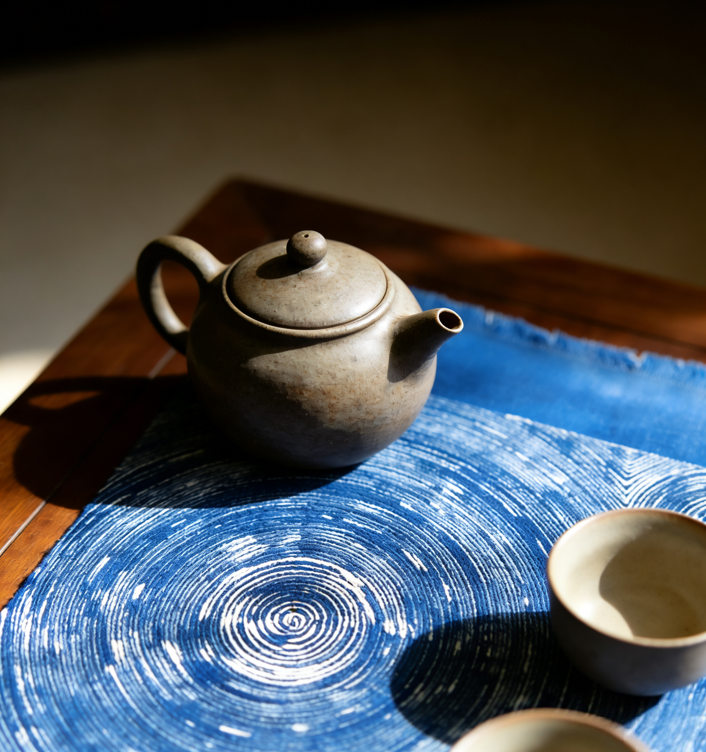 Teapot on a blue textured surface with a wooden background