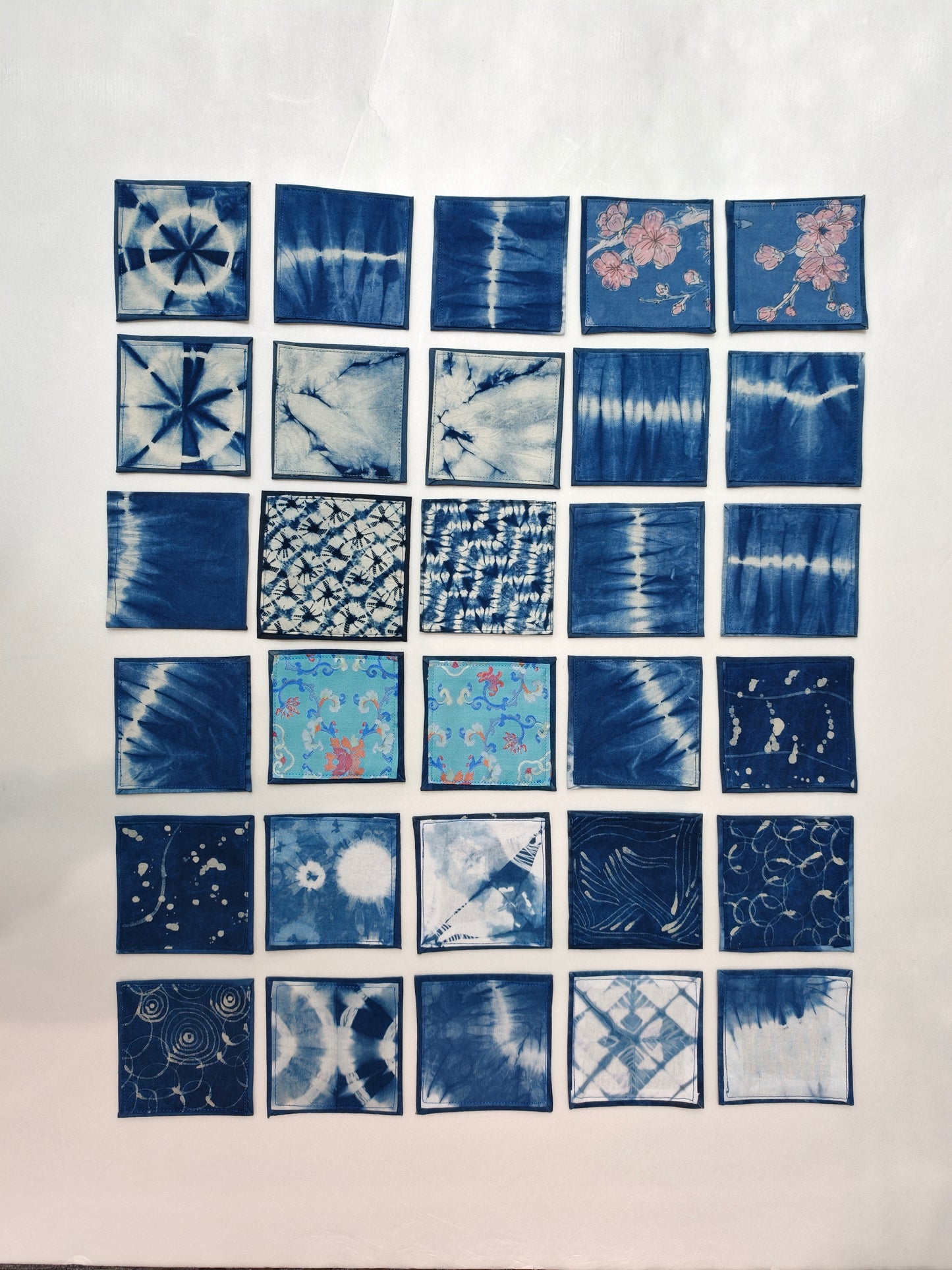 Grid of blue tie-dye fabric samples on a white background