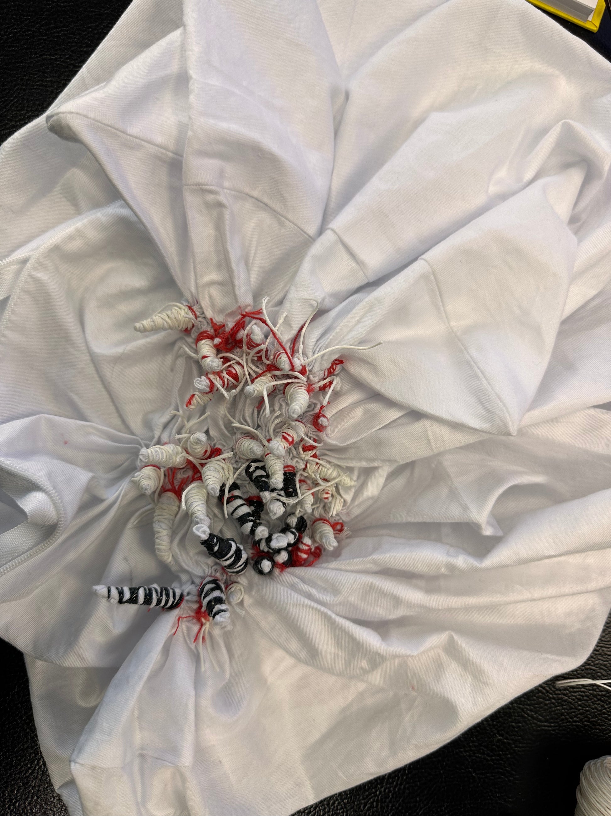 White garment with decorative elements inside a folded white fabric cover