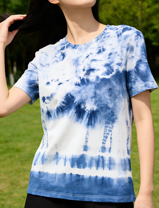 Person wearing a blue and white tie-dye shirt outdoors on a green background