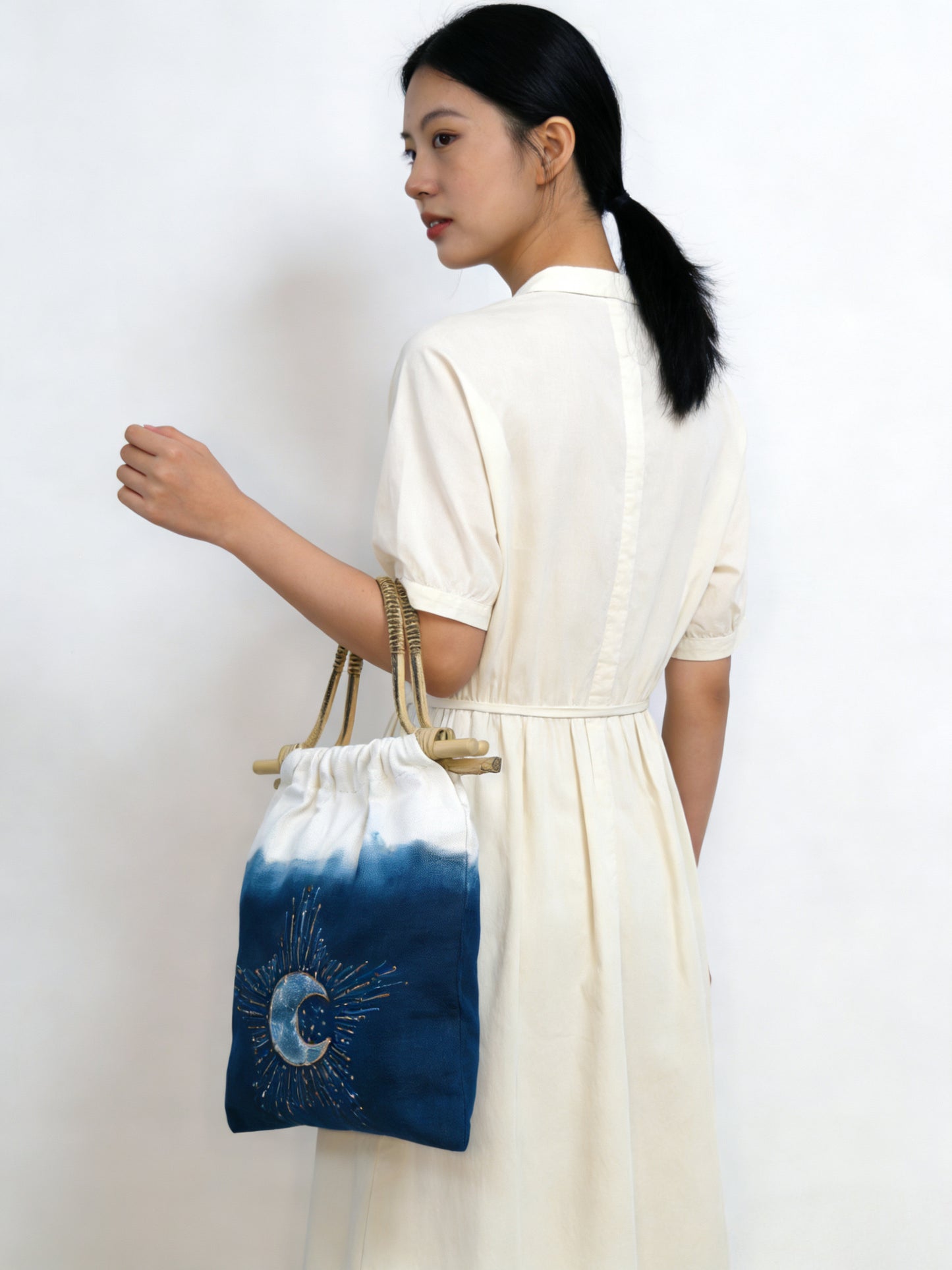 Woman holding a drawstring bag with a blue and white design against a white background