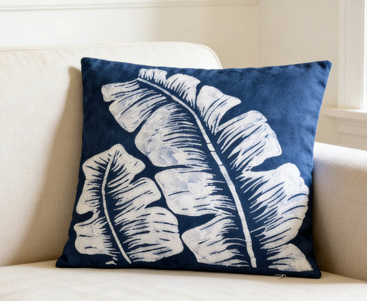 Navy blue pillow with white leaf pattern on a beige couch