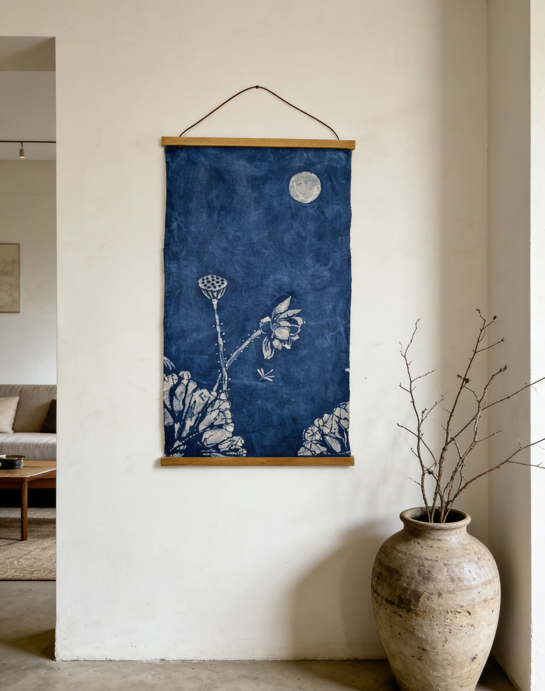 Blue floral artwork hanging on a white wall next to a textured vase.