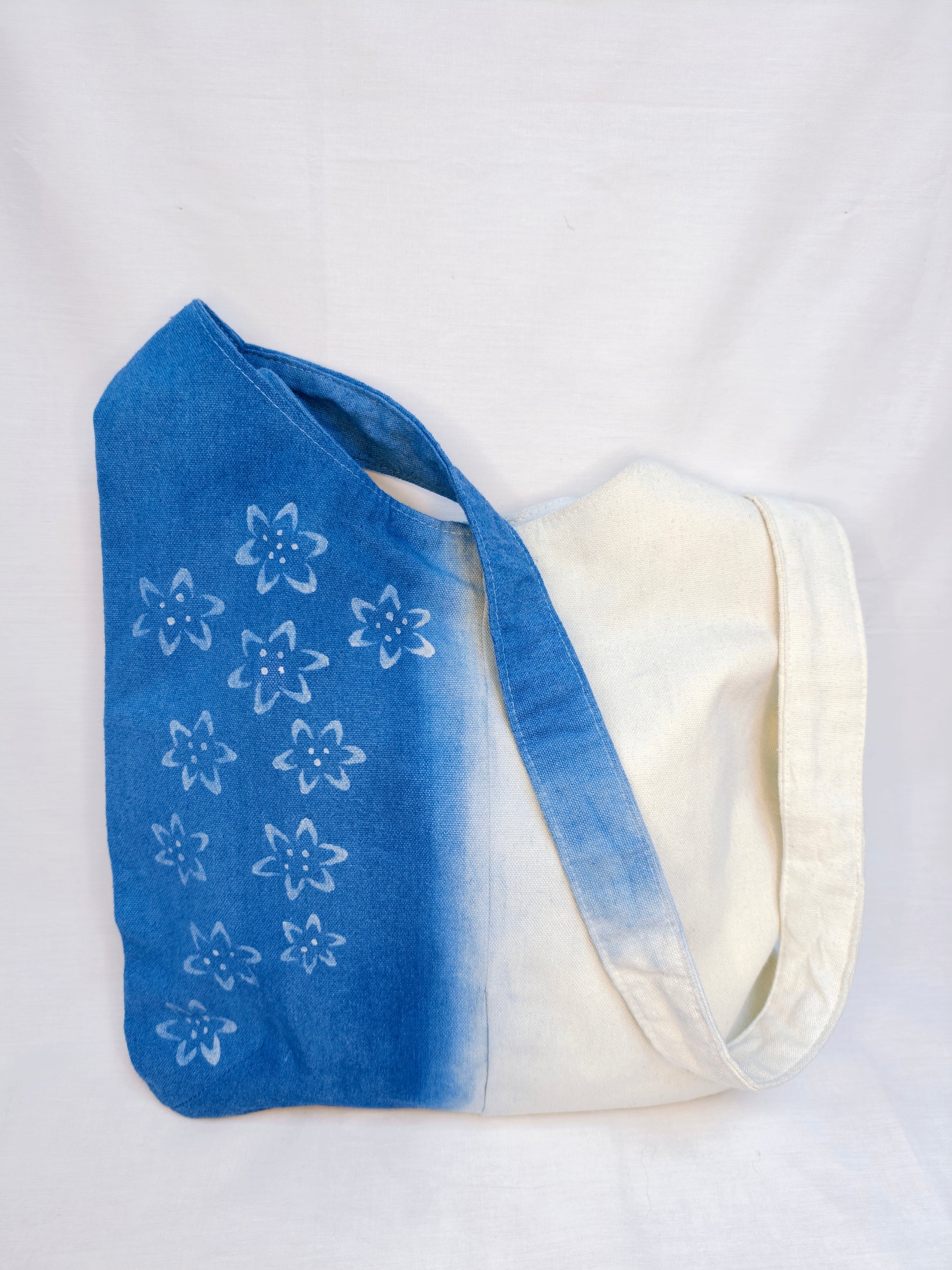 Blue tote bag with white floral patterns on a white background