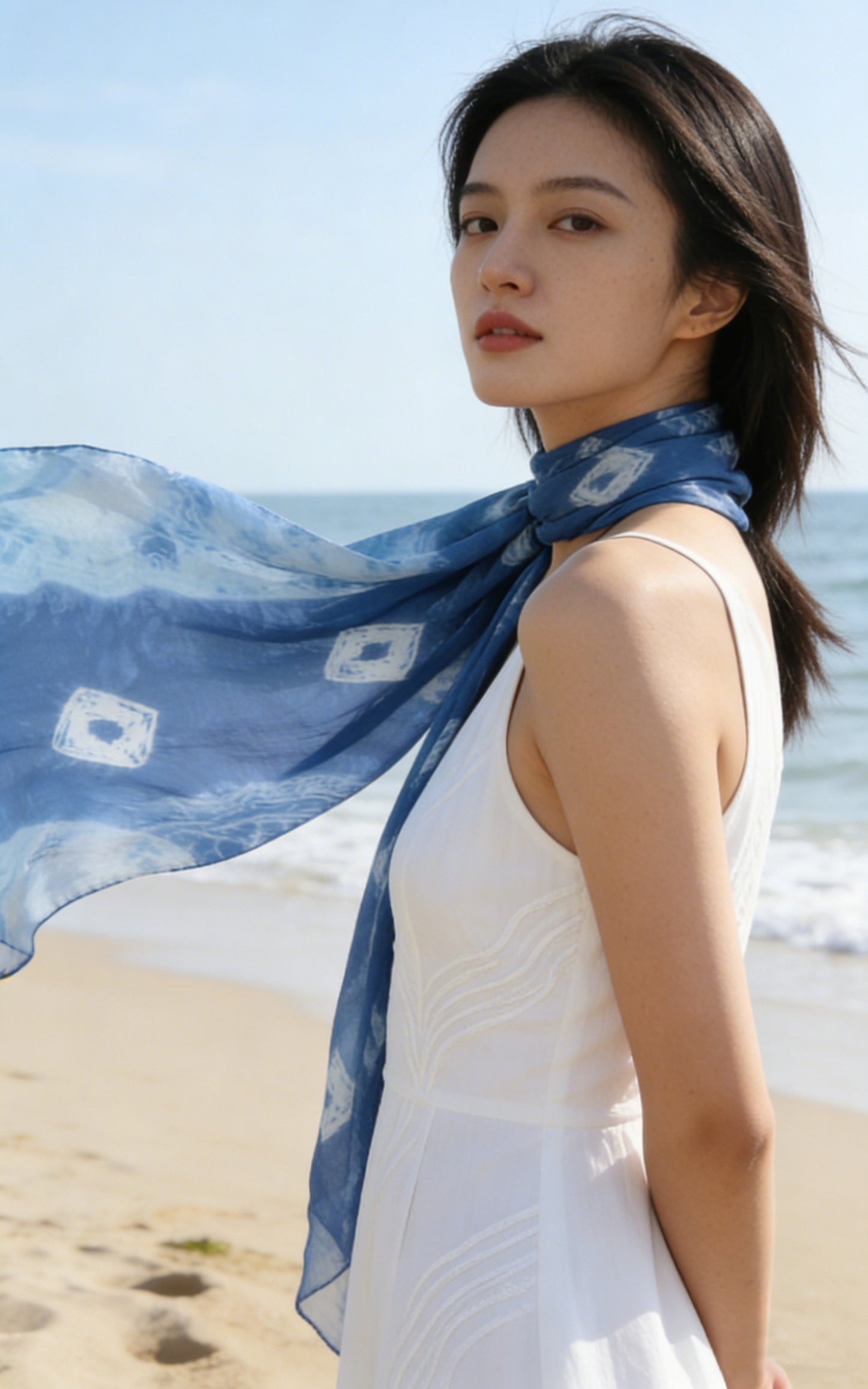 Woman wearing a blue scarf on a beach