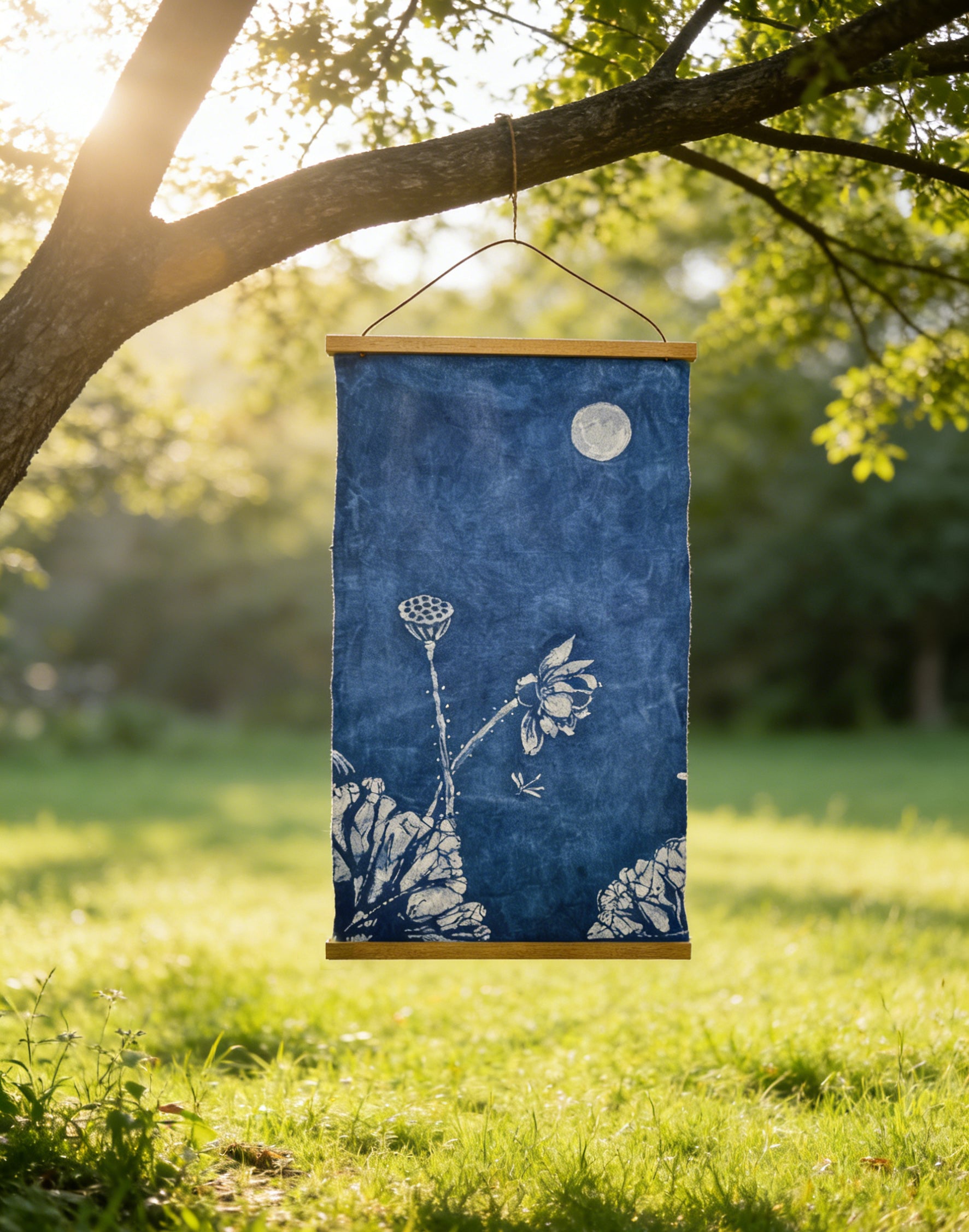 Blue floral fabric hanging from a tree in a grassy field