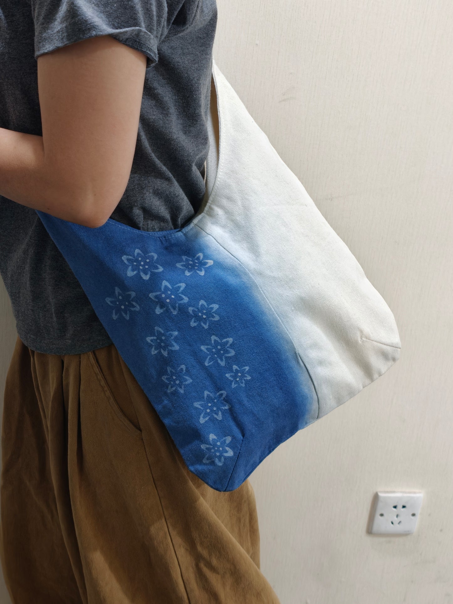 Person holding a blue and white gradient bag with floral patterns.