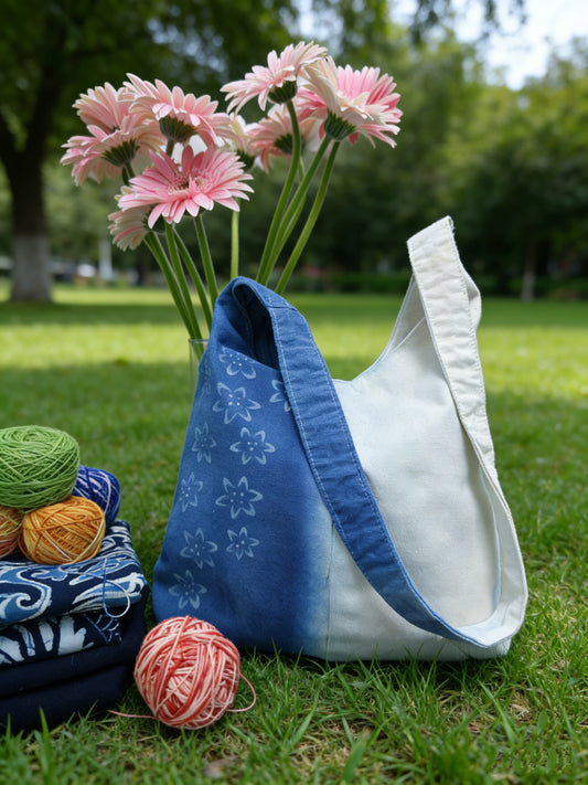 Blue and white tote bag with flowers and yarn on grass