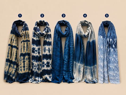 Five indigo tie-dye shawls or scarves displayed side by side against a beige background, numbered 1 to 5 with small blue circles above each item. The scarves show different tie-dye patterns in shades of blue, navy, and cream.