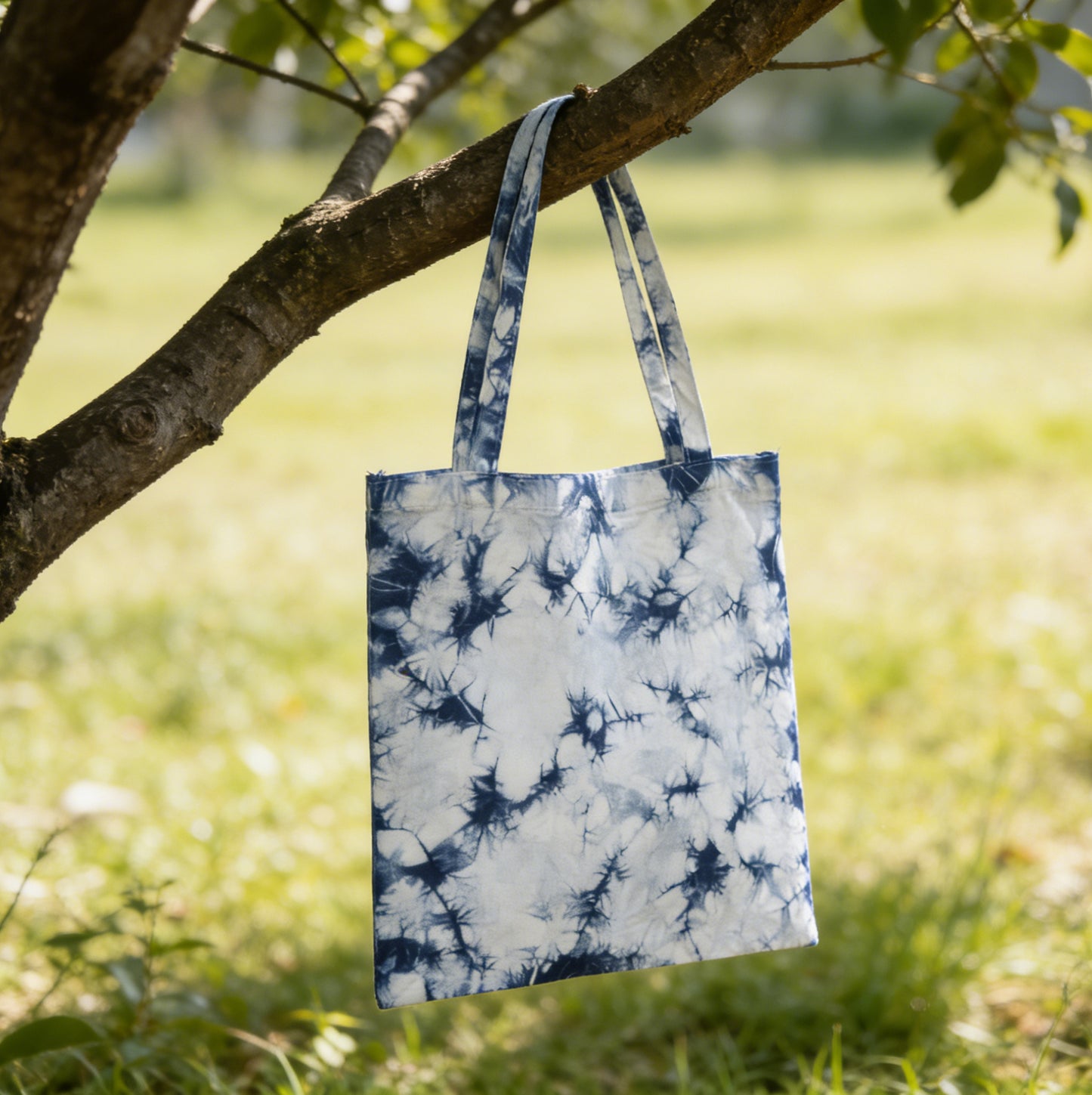 Tie-dye tote bag hanging on a tree branch in a natural setting