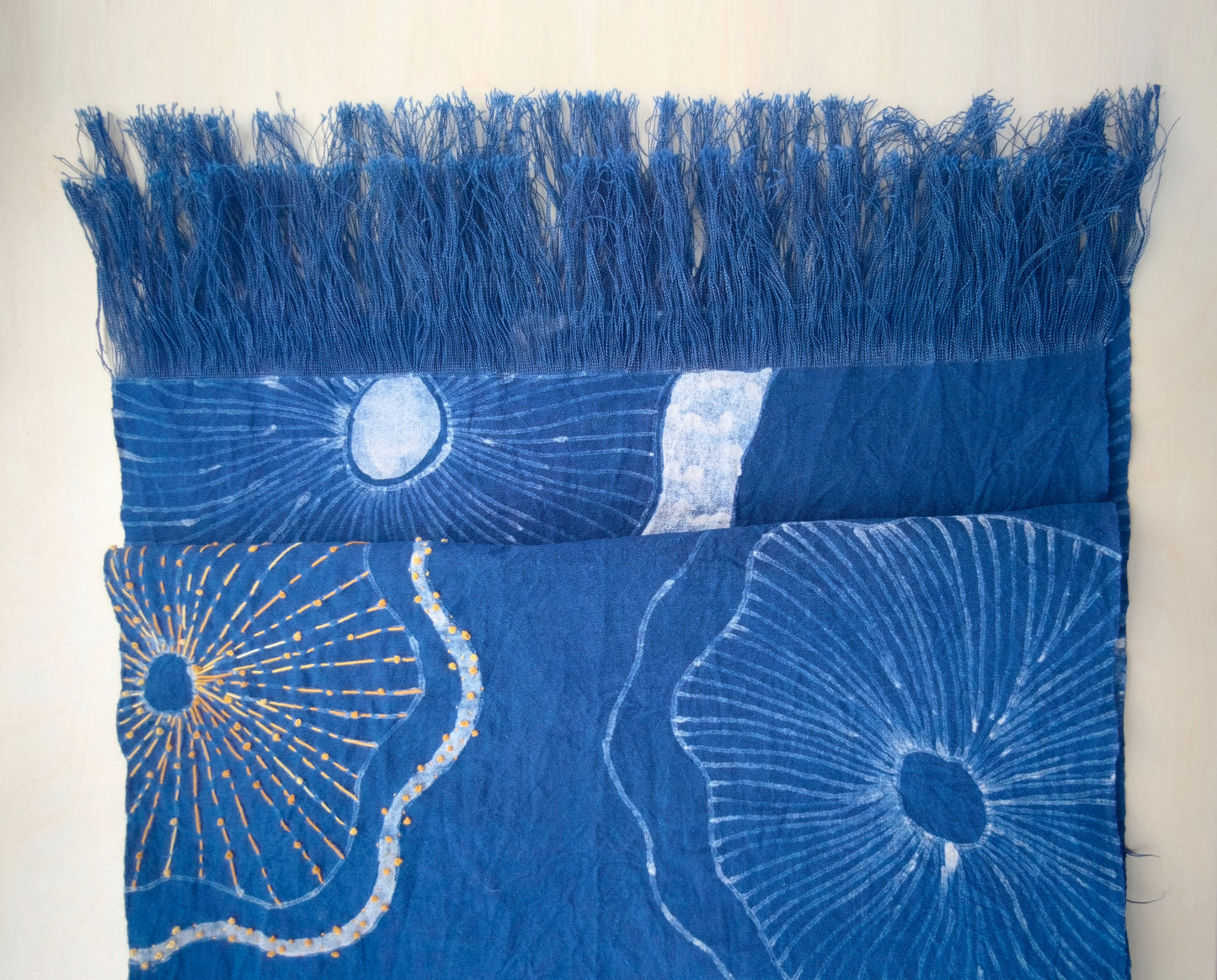 Blue fabric with floral patterns and fringes on a white background