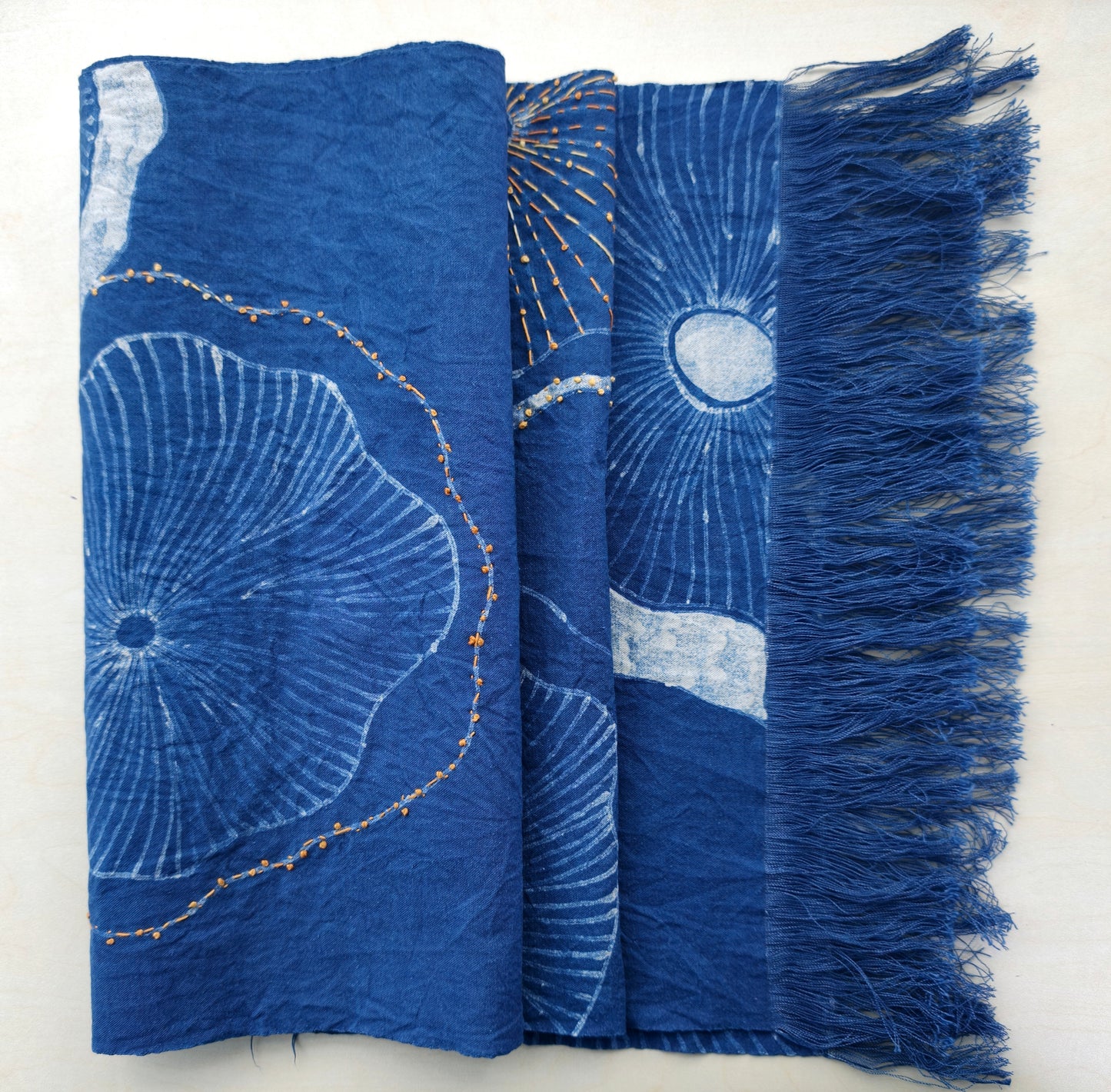 Blue fabric with white patterns and fringes on a white background