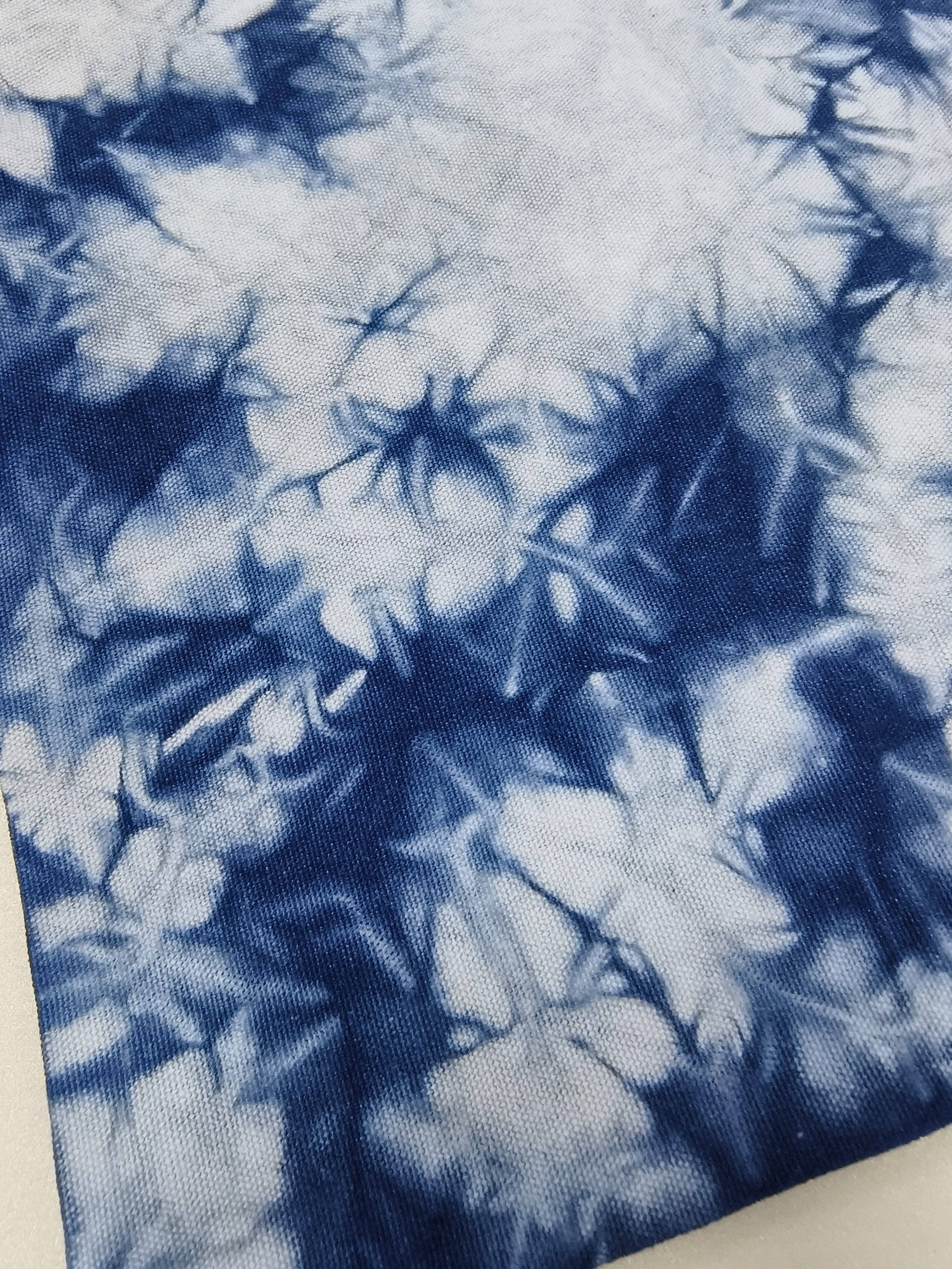 Tie-dye fabric with blue and white pattern on a plain background
