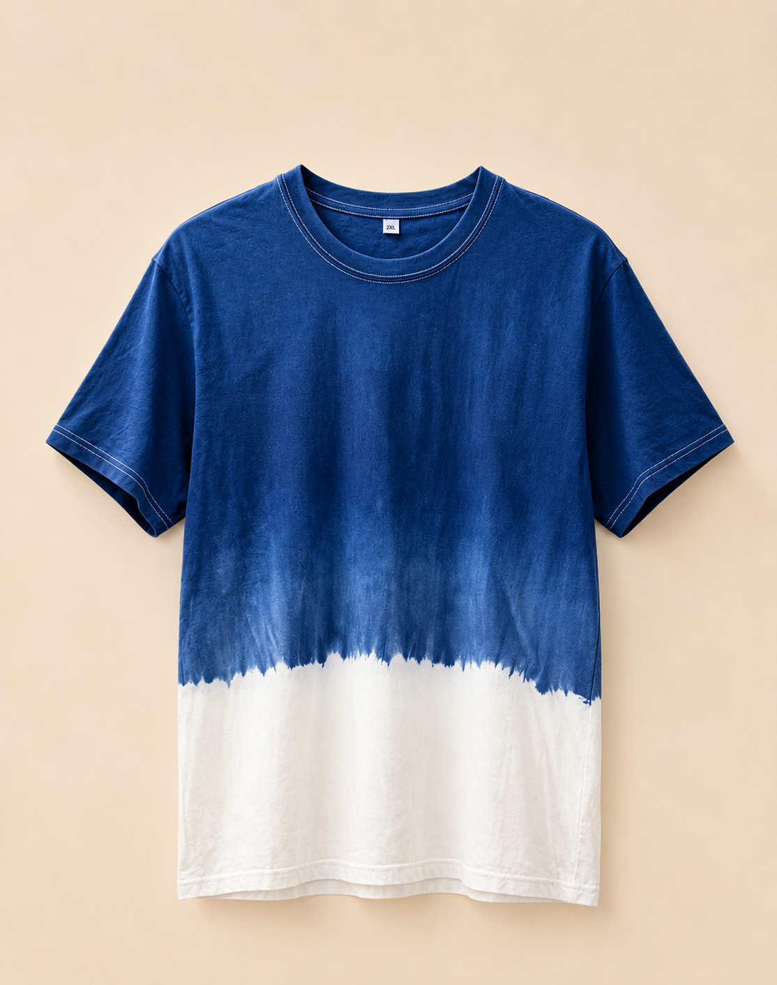 A short-sleeve crewneck t-shirt with a blue and white tie-dye color-blocked design, displayed flat against a solid beige background.